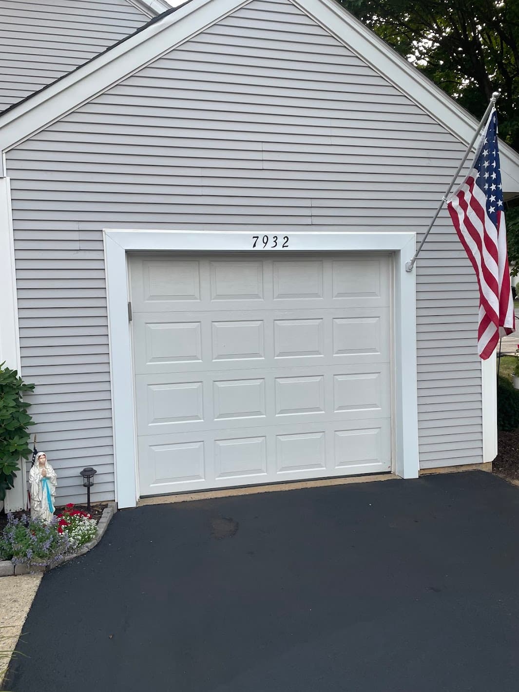 Rebuilt garage-side wall with new siding, white raised-panel door, and fresh trim on a gray-sided home