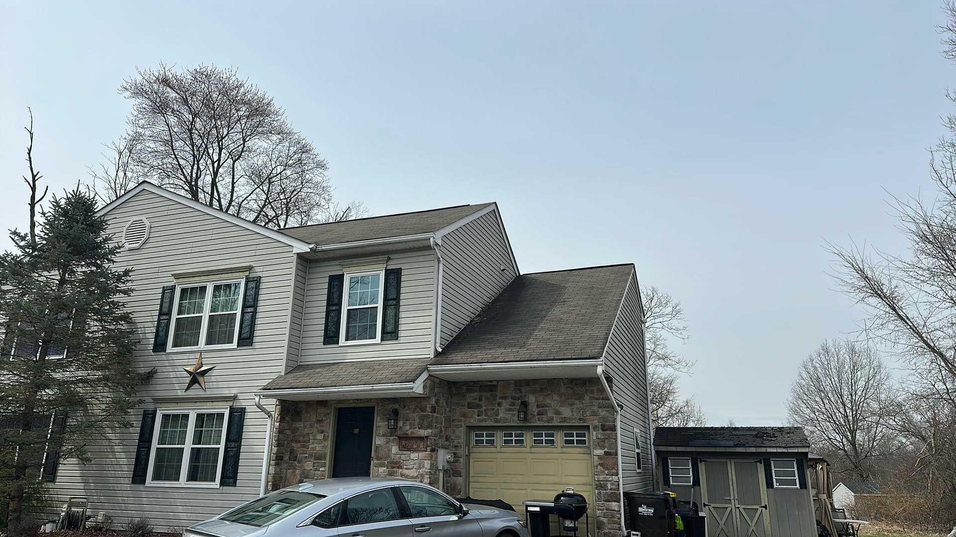 Completed architectural shingle roof on a two-story colonial with stone veneer front and attached garage
