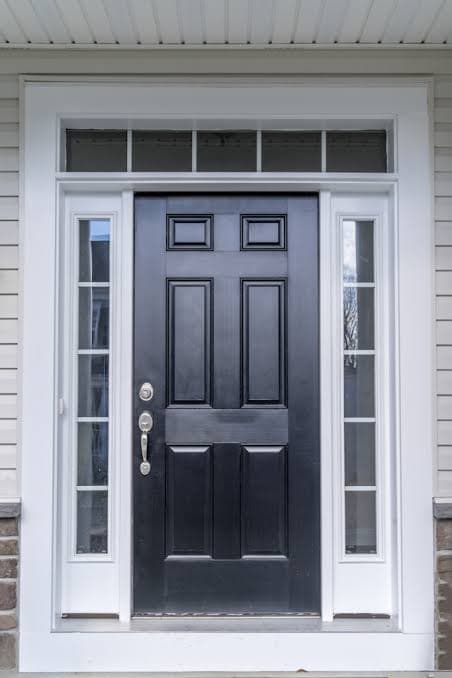 Newly installed black six-panel entry door with glass sidelights and a transom above, set in white trim