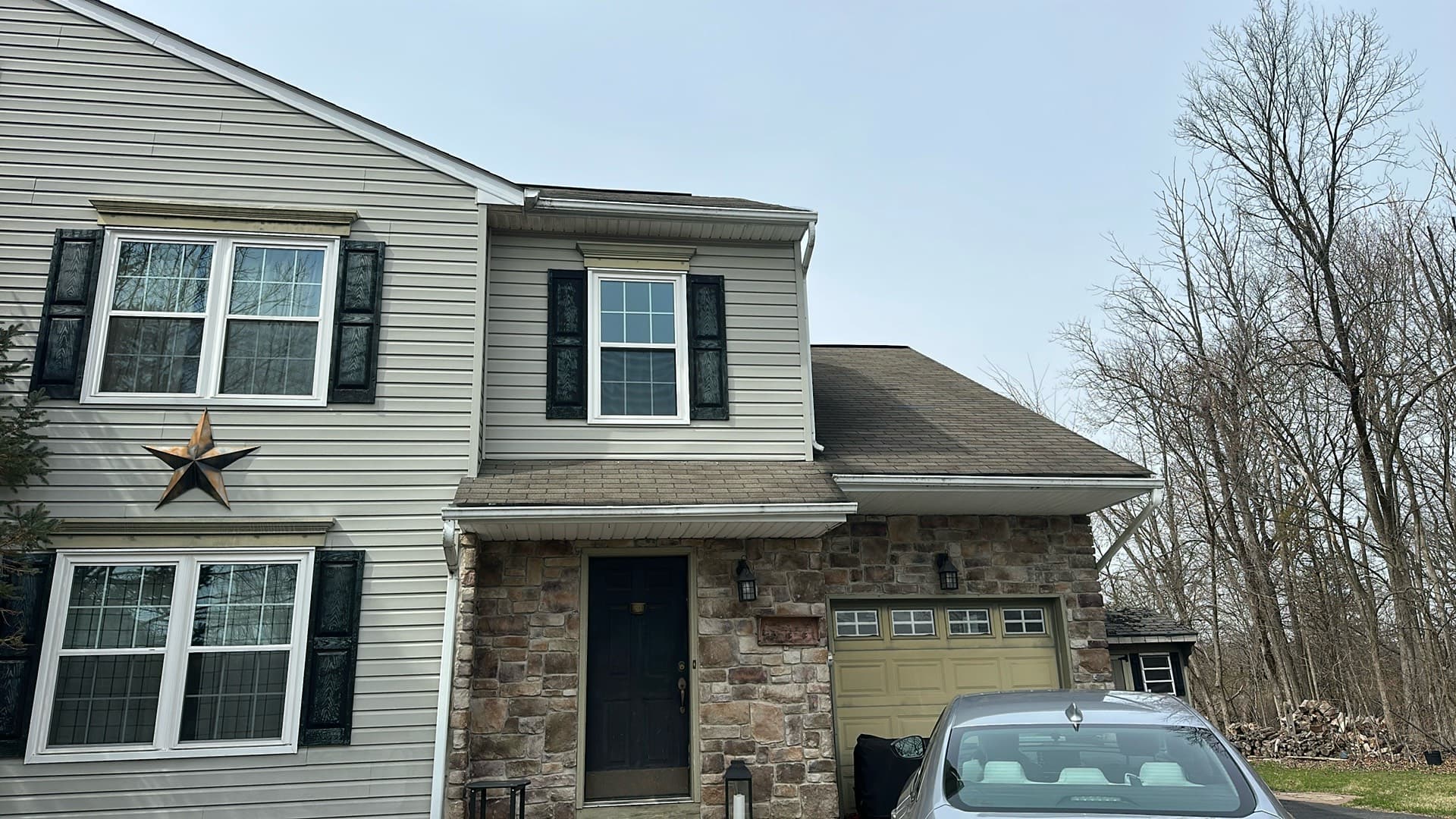 Colonial home with white double-hung replacement windows, black shutters, and a stone-veneer entry